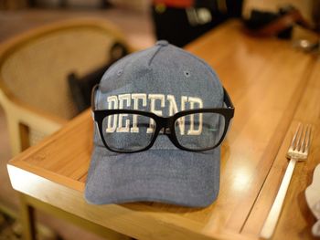 Close-up of eyeglasses and cap on table