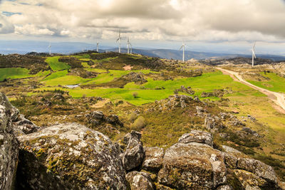 Scenic view of green landscape by sea against sky