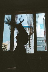 Rear view of silhouette woman seen through glass window