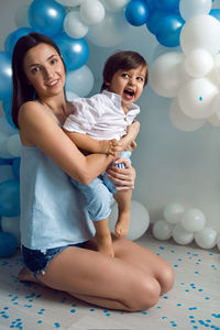 Mom and son on their birthday having fun at home with balloons and number two