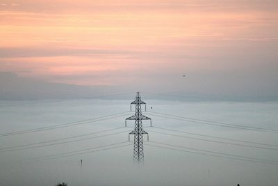 Electricity pylon against sky during sunset