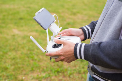 Midsection of man holding mobile phone in field