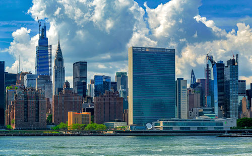 Sea by modern buildings against sky in city