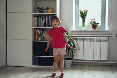 Child warms up before training at home. smiling girl stands on her heels