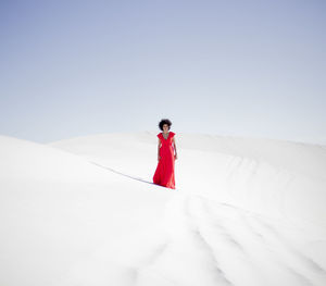 Man standing on snow covered landscape against clear sky