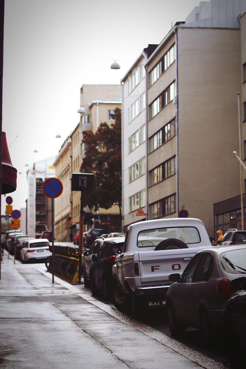 CARS ON ROAD BY BUILDINGS AGAINST SKY