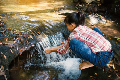 Girl with hands cupped on waterfall