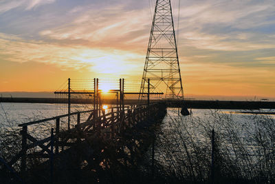 Electricity pylon against sky during sunset