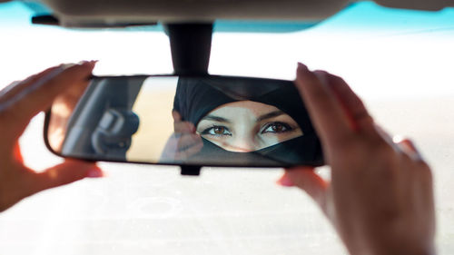 Cropped hands of woman holding rear-view mirror