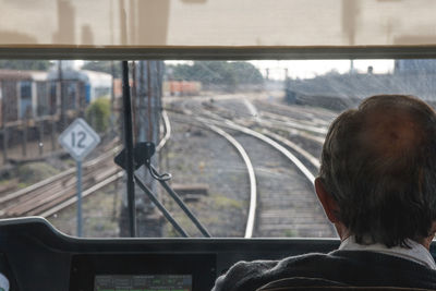 Rear view of man driving train on railroad track