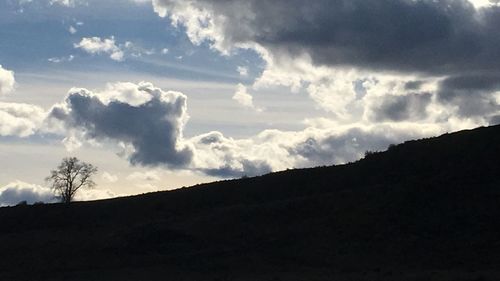 Low angle view of storm clouds over silhouette landscape