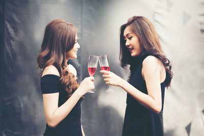 Side view of smiling young friends toasting wineglasses