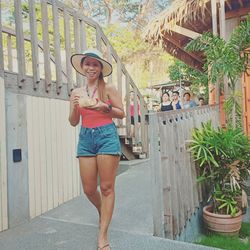 Portrait of smiling mid adult woman wearing hat walking on footpath