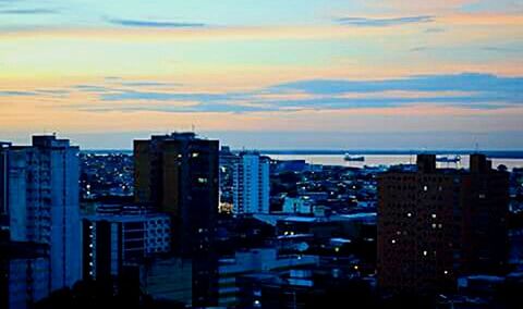 Illuminated cityscape against sky at sunset