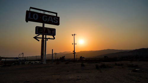 Road sign against sky during sunset