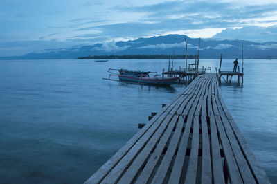 Boat floating in a wwooden traditional dock in blue early morning in manowari, west papua, indonesia 