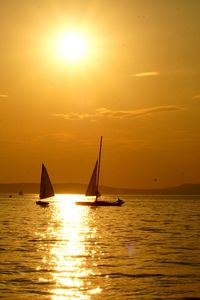 Silhouette sailboat sailing on sea against sky during sunset