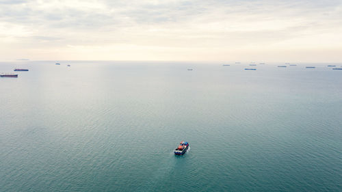 Aerial seascape view and small container ship floating in sea horizon and cloud sky backgroun