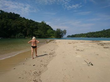 Full length of woman standing on beach against sky