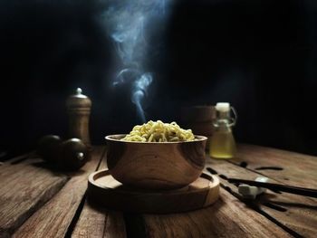 A bowl of hot boiled noodles is ready to eat in a wooden table. dark mood photography concept