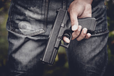 Midsection of man holding handgun