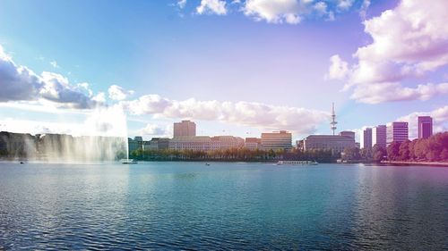 City at waterfront against cloudy sky