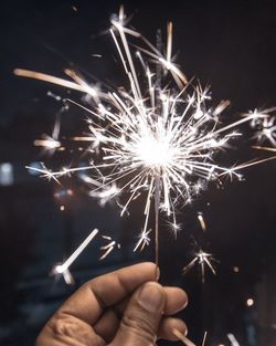 Hand holding firework display at night