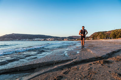Man standing in sea against clear blue sky