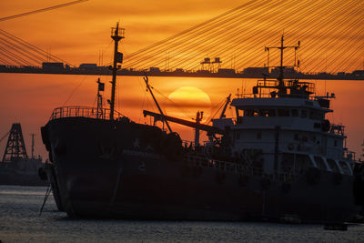 Sailboats moored at harbor against sky during sunset