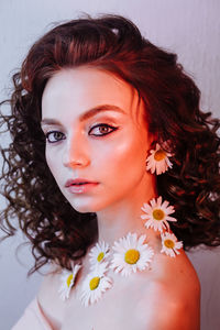 Close-up portrait of beautiful young woman wearing flowers and make-up