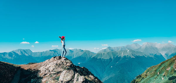 Man standing on snowcapped mountain against blue sky