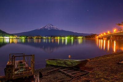 Illuminated pier over lake against sky at night