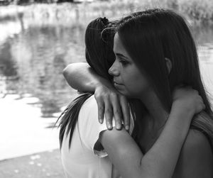 Side view of women hugging by lake