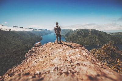 Rear view of man standing on rock against sky