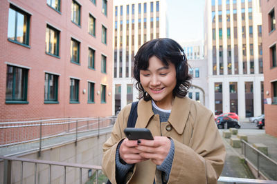 Young woman using mobile phone in city