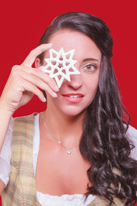 Close-up portrait of woman holding decor against red background