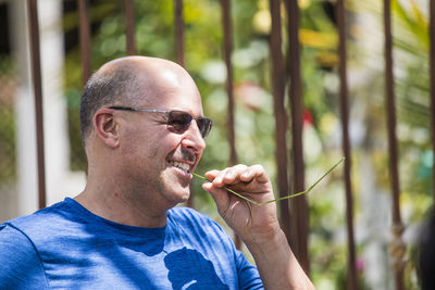 Retired man bites on a blade of grass during vacation.