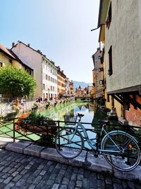 Bicycle parked by canal against buildings in city