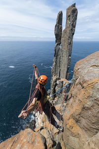 Male adventurer coils up the rope as he scopes his next challenge: two freestanding rock pilars emerging from the ocean in the sea cliffs of cape raoul, in tasmania, australia.