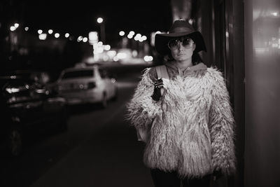 Portrait of woman standing in city at night