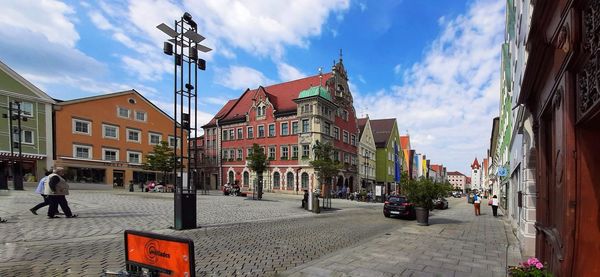 People on street amidst buildings in city against sky