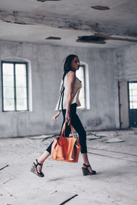 Young woman looking away while standing on floor