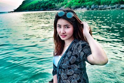Portrait of beautiful young woman standing against sea