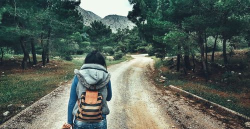 Rear view of female hiker standing on dirt road at field