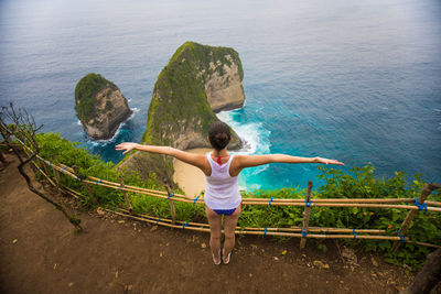 Rear view of girl standing by sea against sky