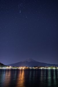 Scenic view of lake and mountains against sky at night