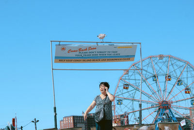 Low angle view of ferris wheel against clear blue sky