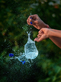 Cropped hands bursting water balloon