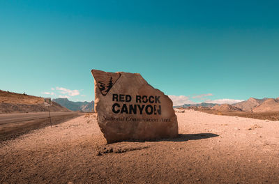 Information sign on desert against sky