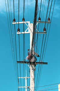 Low angle view of electricity pylon against blue sky